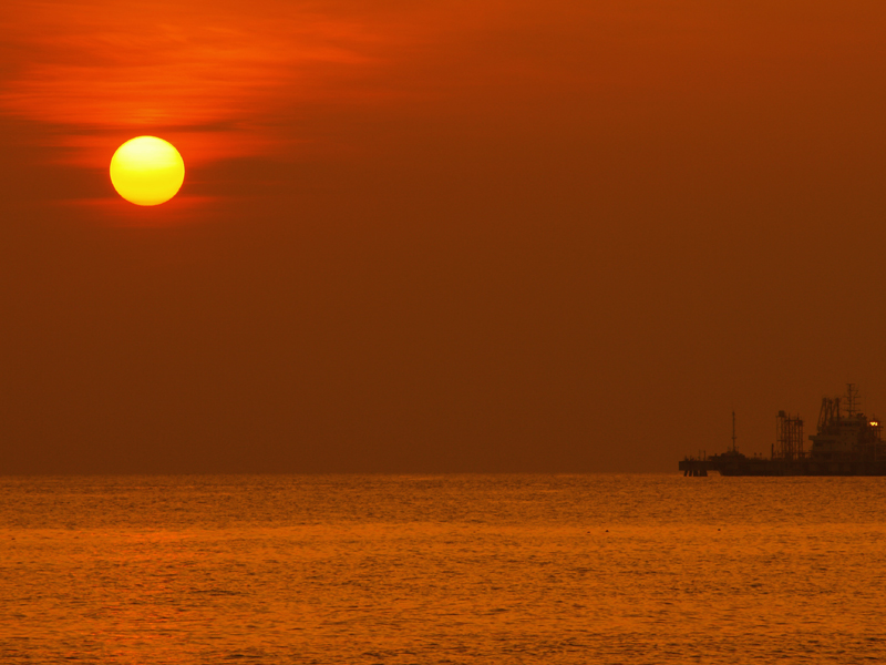 マラッカ海峡に浮かぶ石油コンビナートに沈む夕陽